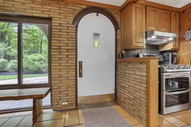 13115 Jack Run Rd, Rockbridge, OH 43149 - kitchen with under cabinet range hood, double oven range, brown cabinetry, and light tile patterned flooring