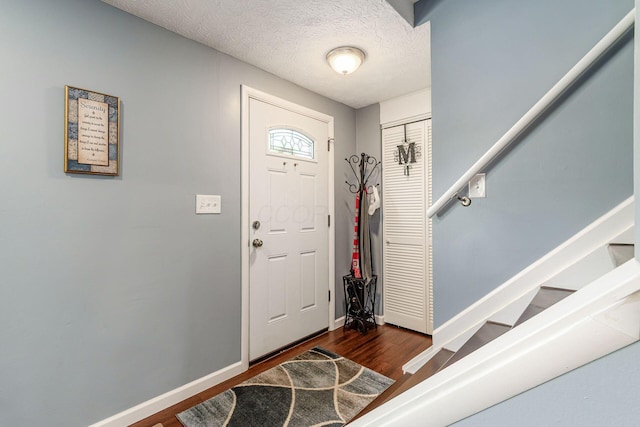 6407 Skywae Dr, Columbus, OH 43229 - foyer entrance featuring dark wood-style flooring, baseboards, stairway, and a textured ceiling