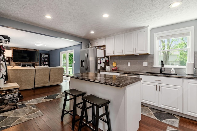 6407 Skywae Dr, Columbus, OH 43229 - kitchen with a sink, dark countertops, stainless steel refrigerator with ice dispenser, a breakfast bar, and dark wood-style flooring