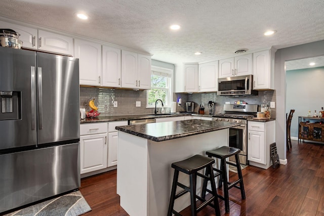 6407 Skywae Dr, Columbus, OH 43229 - kitchen with appliances with stainless steel finishes, dark countertops, dark wood finished floors, backsplash, and recessed lighting