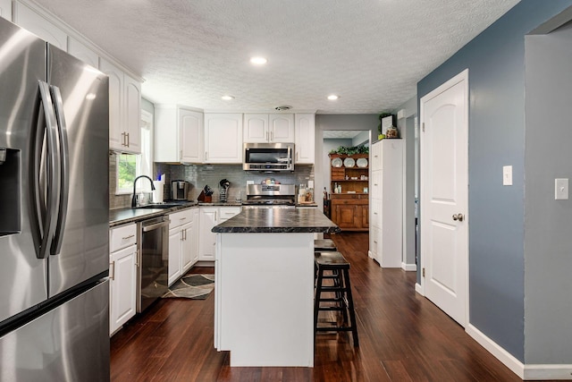 6407 Skywae Dr, Columbus, OH 43229 - kitchen with appliances with stainless steel finishes, dark countertops, a sink, a breakfast bar, and recessed lighting