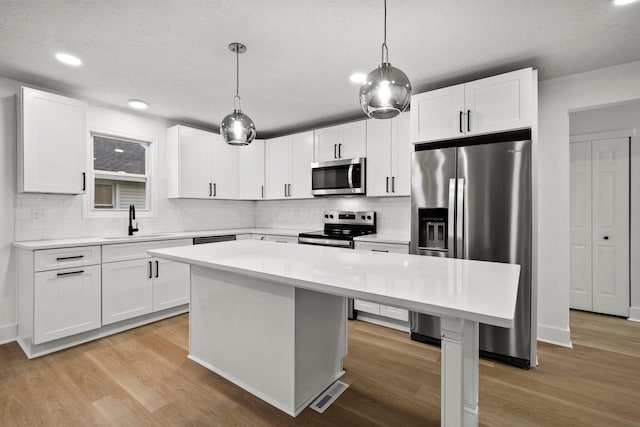 1006 Midland Ave, Columbus, OH 43223 - kitchen featuring appliances with stainless steel finishes, a sink, a kitchen island, light countertops, and white cabinetry