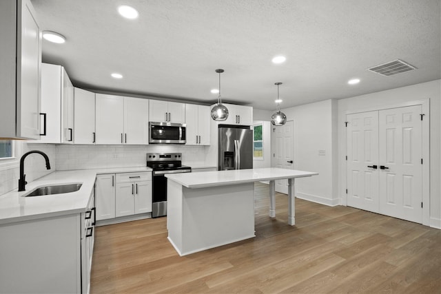 1006 Midland Ave, Columbus, OH 43223 - kitchen featuring stainless steel appliances, a sink, light wood-style flooring, tasteful backsplash, and a breakfast bar