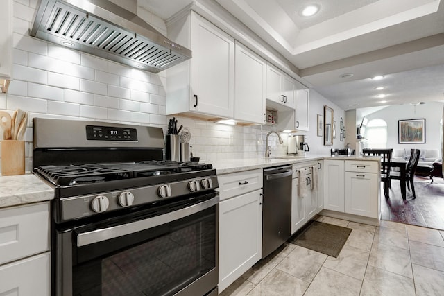 2539 Trotterslane Dr, Columbus, OH 43235 - kitchen with stainless steel appliances, wall chimney range hood, a sink, white cabinets, and a peninsula