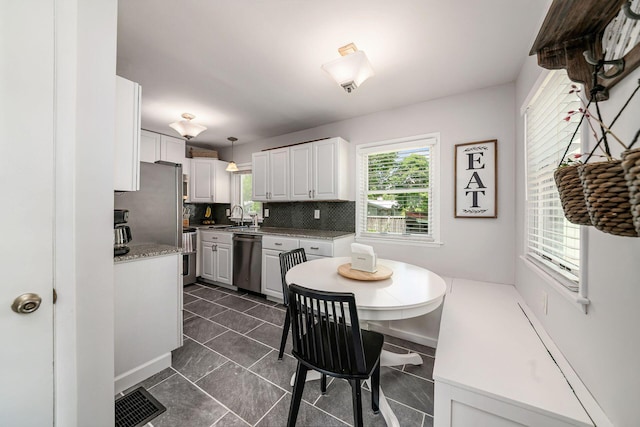2380 Cranford Rd, Upper Arlington, OH 43221 - kitchen featuring stainless steel appliances, a sink, backsplash, white cabinetry, and hanging light fixtures
