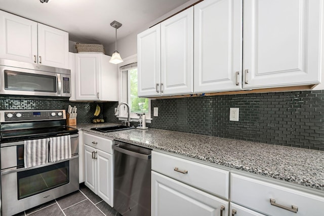 2380 Cranford Rd, Upper Arlington, OH 43221 - kitchen featuring appliances with stainless steel finishes, a sink, dark tile patterned flooring, white cabinets, and light stone countertops
