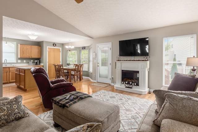 4989 Edgeley Dr, Hilliard, OH 43026 - living room with vaulted ceiling, plenty of natural light, a chandelier, a glass covered fireplace, and light wood-type flooring