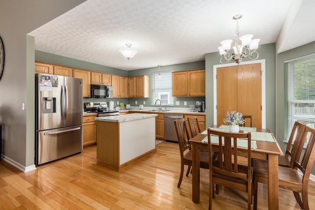 4989 Edgeley Dr, Hilliard, OH 43026 - kitchen featuring appliances with stainless steel finishes, light countertops, a chandelier, light wood-style floors, and a center island