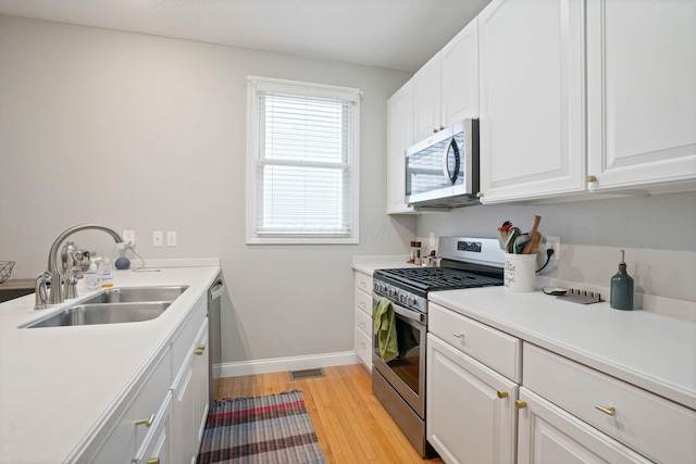 963 Delaware Ave, Columbus, OH 43201 - kitchen with appliances with stainless steel finishes, a sink, light wood-style flooring, and white cabinetry