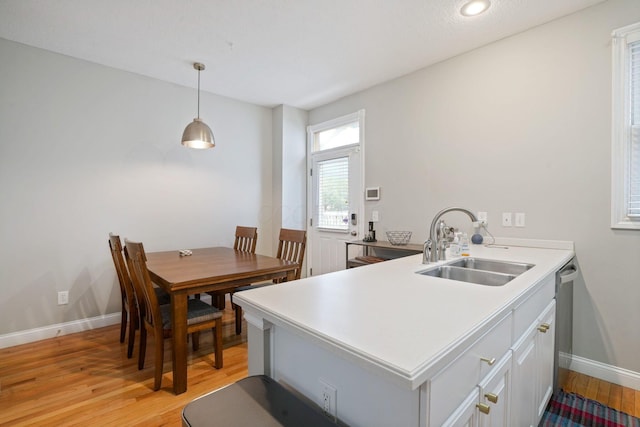 963 Delaware Ave, Columbus, OH 43201 - kitchen featuring a sink, light wood finished floors, baseboards, white cabinetry, and decorative light fixtures