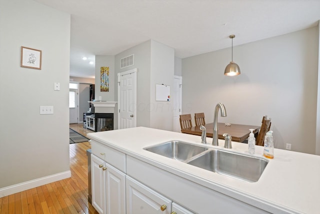 963 Delaware Ave, Columbus, OH 43201 - kitchen featuring a sink, light wood-style flooring, baseboards, white cabinetry, and pendant lighting