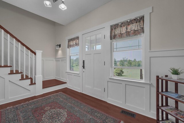 14980 Robins Rd, Johnstown, OH 43031 - foyer entrance featuring a decorative wall, dark wood-type flooring, healthy amount of natural light, a wainscoted wall, and stairs