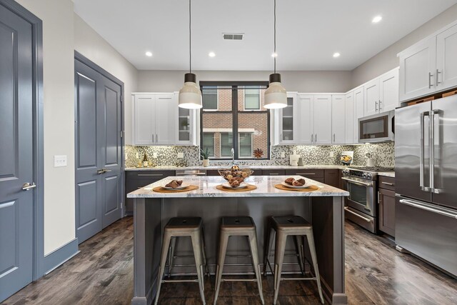 123 Aston Row Ln, Columbus, OH 43201 - kitchen featuring premium appliances, dark wood finished floors, glass insert cabinets, a breakfast bar, and recessed lighting