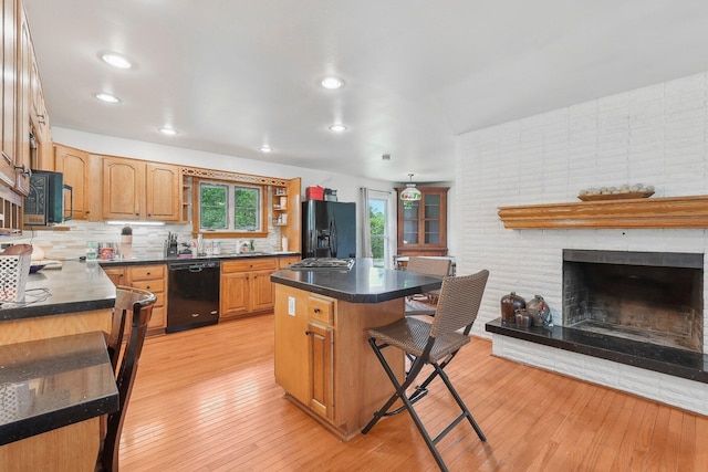 385 Taylor Blair Rd, West Jefferson, OH 43162 - kitchen with black appliances, a breakfast bar, dark countertops, decorative backsplash, and light wood-style floors