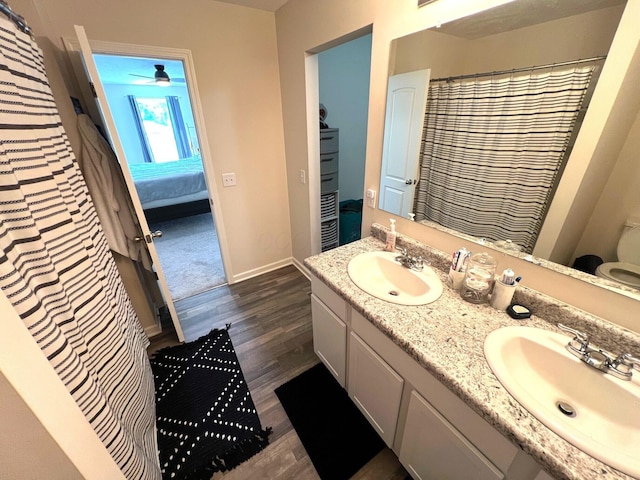 324 Genoa Rd, Commercial Point, OH 43116 - ensuite bathroom featuring double vanity, wood finished floors, baseboards, ceiling fan, and toilet