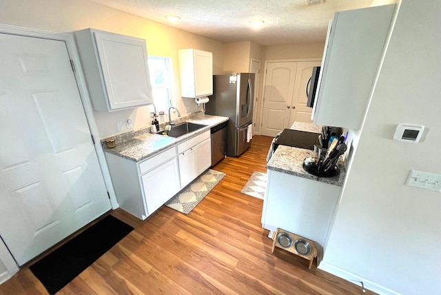 324 Genoa Rd, Commercial Point, OH 43116 - kitchen featuring a sink, appliances with stainless steel finishes, light wood finished floors, white cabinetry, and a textured ceiling