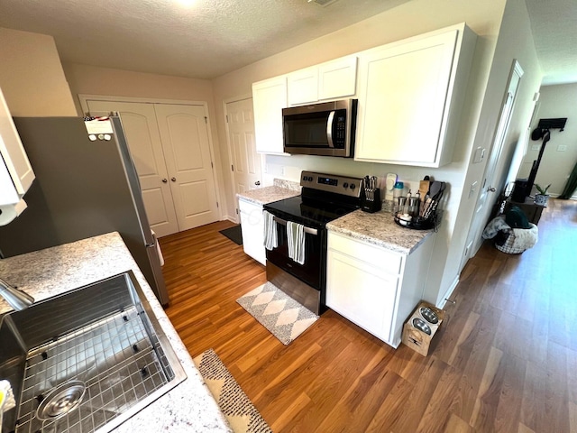 324 Genoa Rd, Commercial Point, OH 43116 - kitchen featuring appliances with stainless steel finishes, dark wood-style flooring, white cabinets, a textured ceiling, and light stone counters