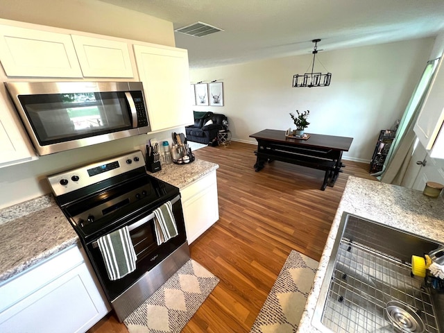 324 Genoa Rd, Commercial Point, OH 43116 - kitchen with stainless steel appliances, dark wood finished floors, white cabinetry, hanging light fixtures, and baseboards