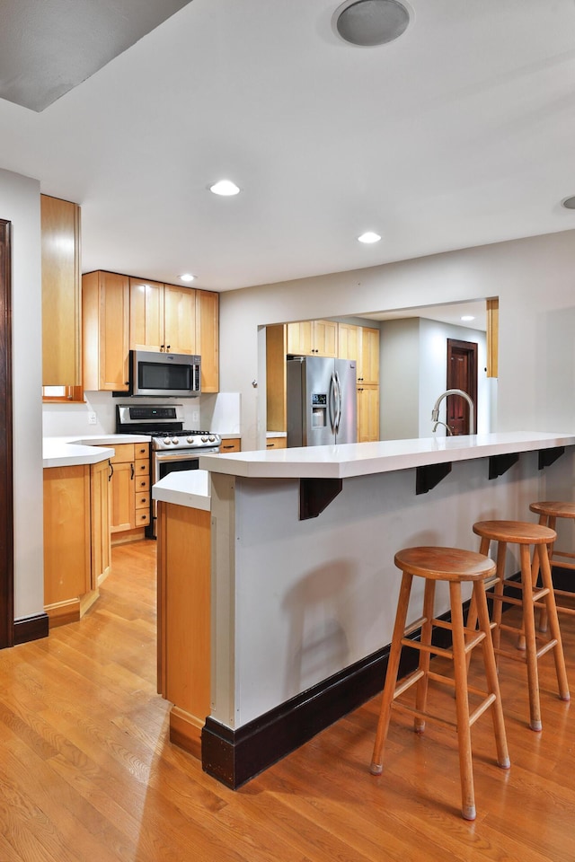 72 Glenmont Ave, Columbus, OH 43214 - kitchen featuring appliances with stainless steel finishes, a breakfast bar area, light wood finished floors, light countertops, and recessed lighting