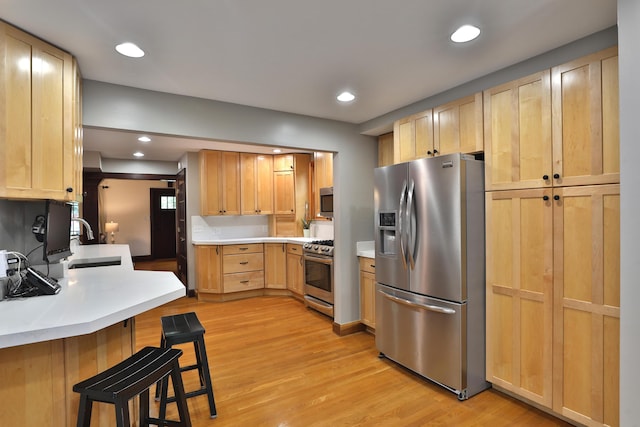72 Glenmont Ave, Columbus, OH 43214 - kitchen with appliances with stainless steel finishes, a sink, a kitchen breakfast bar, light wood finished floors, and light brown cabinets