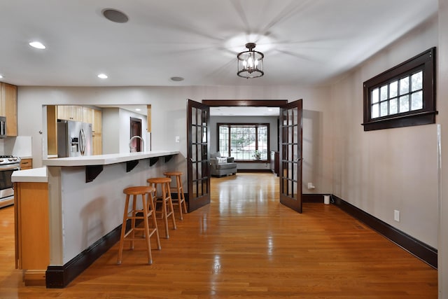 72 Glenmont Ave, Columbus, OH 43214 - kitchen with appliances with stainless steel finishes, french doors, wood finished floors, a breakfast bar area, and a peninsula