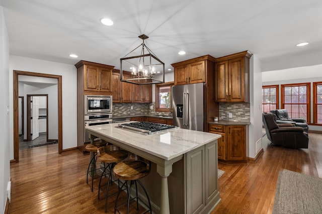 2656 Fair Ave, Columbus, OH 43209 - kitchen featuring appliances with stainless steel finishes, backsplash, a kitchen breakfast bar, wood finished floors, and recessed lighting