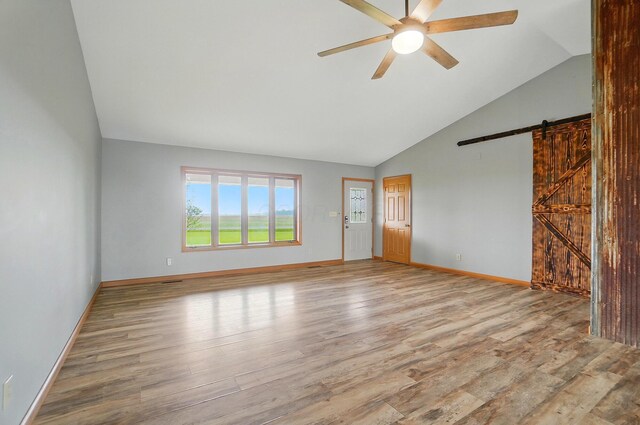 2580 Lafayette Plain City Rd, London, OH 43140 - unfurnished living room with a barn door, vaulted ceiling, ceiling fan, wood finished floors, and baseboards