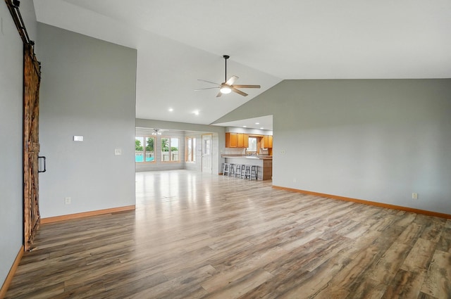 2580 Lafayette Plain City Rd, London, OH 43140 - unfurnished living room with ceiling fan, light wood-type flooring, a barn door, lofted ceiling, and baseboards