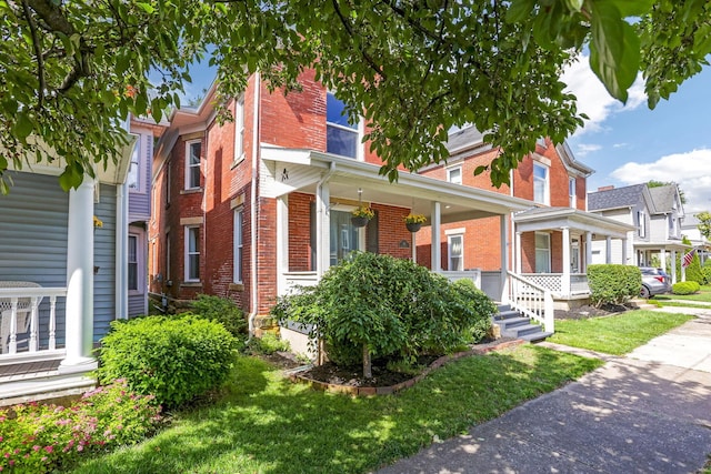 141 E 5th Ave, Lancaster, OH 43130 - view of front of home with brick siding, covered porch, and a front lawn