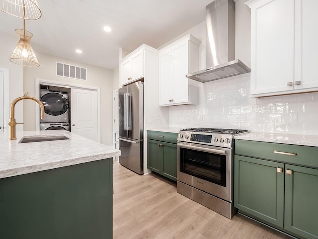 6633 Dale Dr Unit 417, Dublin, OH 43017 - kitchen with green cabinets, stainless steel appliances, stacked washer / drying machine, wall chimney range hood, and a sink