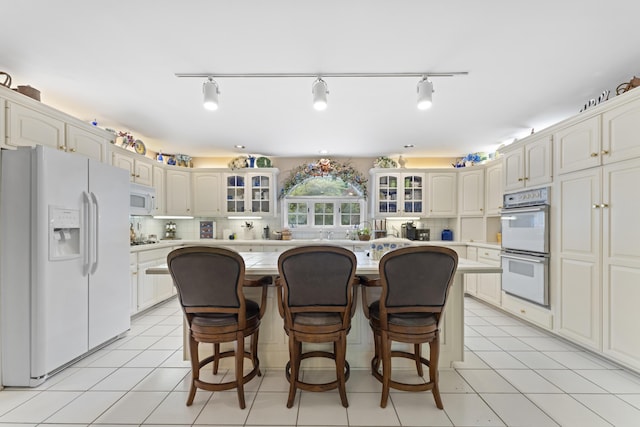 8039 Crossgate Ct S, Dublin, OH 43017 - kitchen featuring white appliances, glass insert cabinets, a center island, and a kitchen breakfast bar