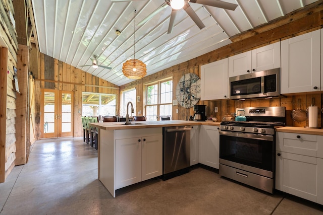 15216 Grove Rd SW Unit Tp142, Port Washington, OH 43837 - kitchen featuring appliances with stainless steel finishes, lofted ceiling, wooden walls, a peninsula, and white cabinetry