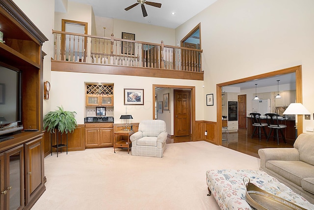 5714 Zetland Ct, Dublin, OH 43017 - living area with a ceiling fan, a wainscoted wall, a towering ceiling, light carpet, and wooden walls
