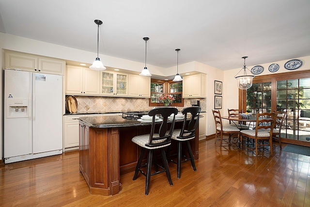 5714 Zetland Ct, Dublin, OH 43017 - kitchen with white refrigerator with ice dispenser, wood finished floors, a kitchen island, and glass insert cabinets