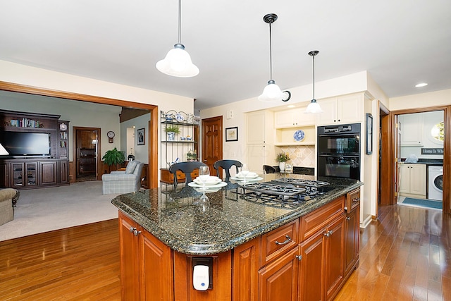 5714 Zetland Ct, Dublin, OH 43017 - kitchen featuring washer / dryer, black appliances, open floor plan, and wood finished floors