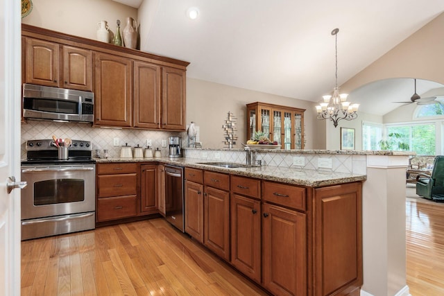 165 Tinley Park Cir, Delaware, OH 43015 - kitchen with stainless steel appliances, vaulted ceiling, a peninsula, brown cabinets, and light wood-type flooring