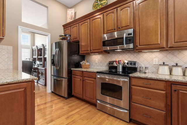 165 Tinley Park Cir, Delaware, OH 43015 - kitchen featuring appliances with stainless steel finishes, light wood-style flooring, tasteful backsplash, and light stone countertops