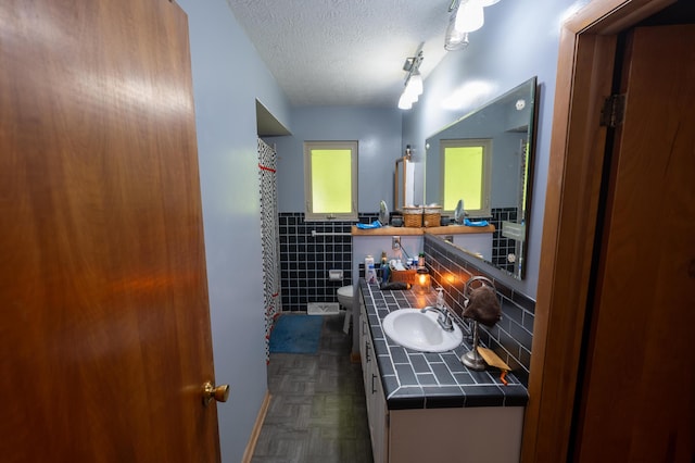 9442 Mitchell Dewitt Rd, Plain City, OH 43064 - bathroom with tile walls, a textured ceiling, toilet, double vanity, and wainscoting