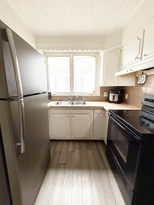 313 E Auburn Ave, Bellefontaine, OH 43311 - kitchen with freestanding refrigerator, black electric range oven, a sink, white cabinets, and under cabinet range hood