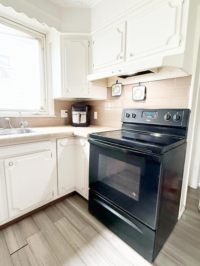 313 E Auburn Ave, Bellefontaine, OH 43311 - kitchen with black electric range, white cabinetry, light wood finished floors, light countertops, and a sink
