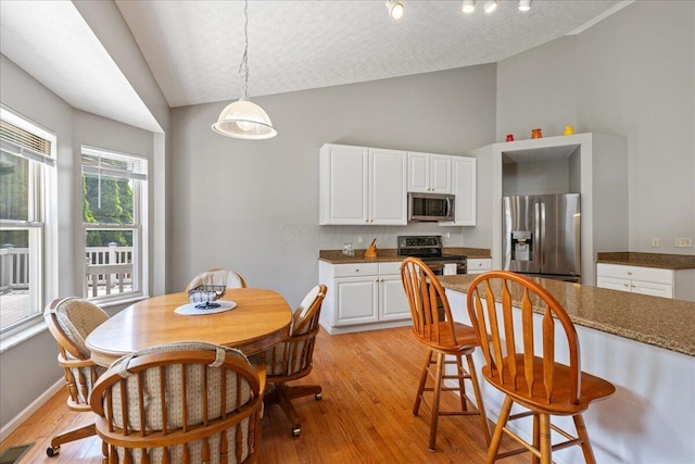 2880 Longridge Way, Grove City, OH 43123 - dining area with light wood-type flooring, a textured ceiling, high vaulted ceiling, and baseboards