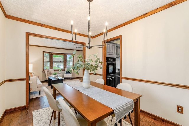 6392 Hilltop Ave, Reynoldsburg, OH 43068 - dining room with a chandelier, a textured ceiling, wood finished floors, ornamental molding, and baseboards