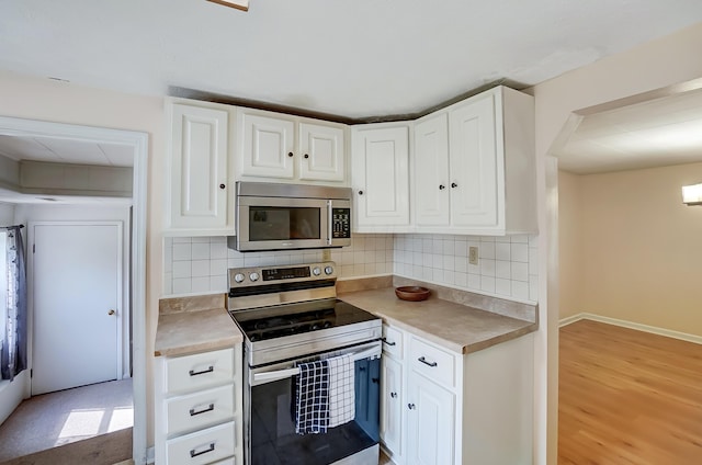 1036 State Route 247, Hillsboro, OH 45133 - kitchen with appliances with stainless steel finishes, white cabinets, light countertops, decorative backsplash, and light wood-type flooring