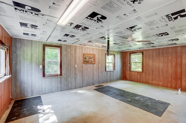 1036 State Route 247, Hillsboro, OH 45133 - spare room featuring wood walls, healthy amount of natural light, unfinished concrete flooring, and a ceiling fan