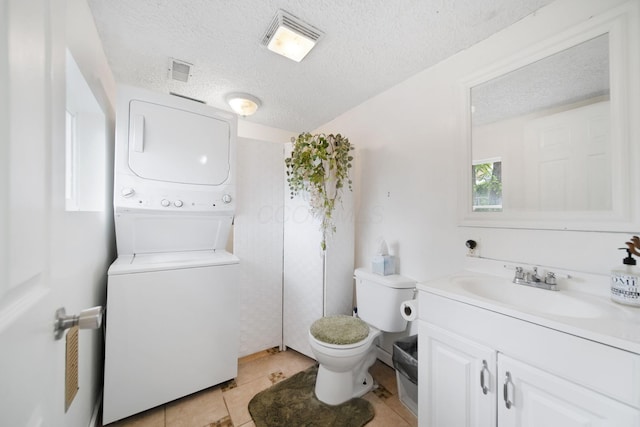173 Highland Ave, Buckeye Lake, OH 43008 - bathroom with estacked washer and dryer, toilet, vanity, a textured ceiling, and tile patterned floors