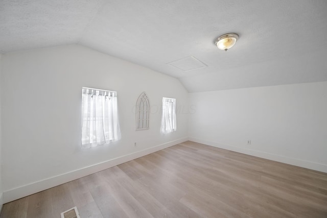 173 Highland Ave, Buckeye Lake, OH 43008 - additional living space featuring lofted ceiling, baseboards, light wood-style floors, a textured ceiling, and attic access