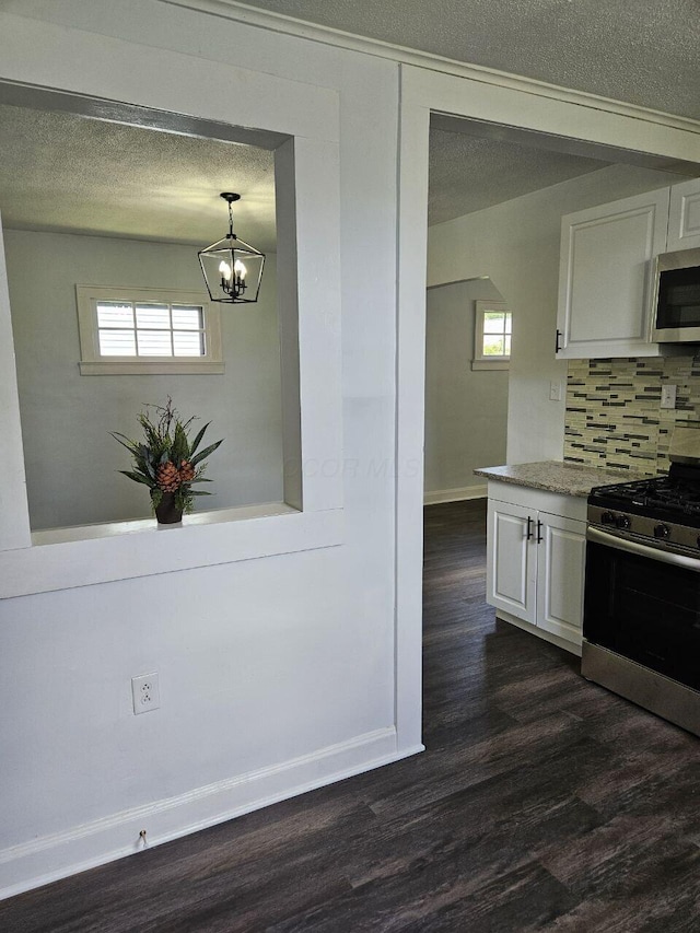 2889 E 12th Ave, Columbus, OH 43219 - kitchen featuring appliances with stainless steel finishes, dark wood-type flooring, white cabinetry, baseboards, and a textured ceiling