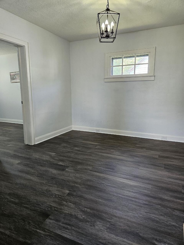 2889 E 12th Ave, Columbus, OH 43219 - unfurnished room with baseboards, a textured ceiling, a chandelier, and dark wood-type flooring