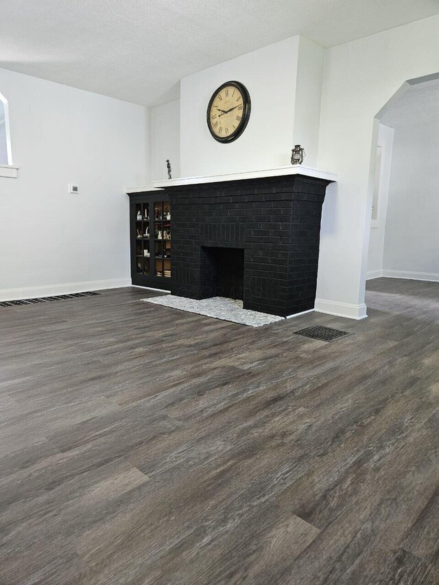 2889 E 12th Ave, Columbus, OH 43219 - unfurnished living room featuring wood finished floors, baseboards, a brick fireplace, and arched walkways