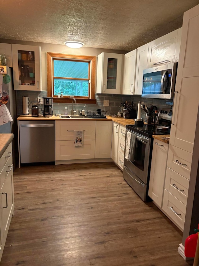 2630 Bella Via Ave, Columbus, OH 43231 - kitchen with appliances with stainless steel finishes, white cabinetry, a textured ceiling, a sink, and glass insert cabinets